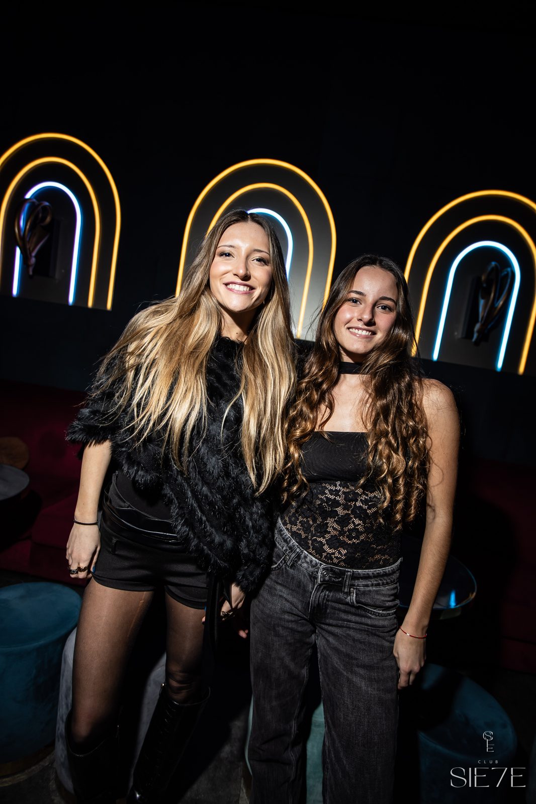 Amigas posando bajo el neon rainbow en la Clase de Coctelería · Club Sie7e